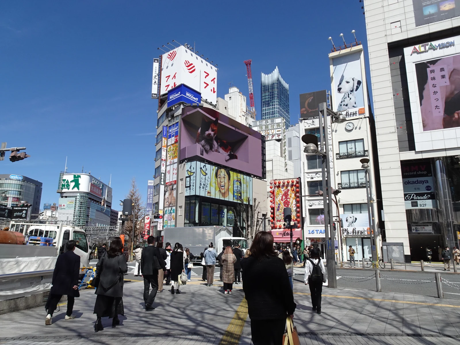 JR Shinjuku Station East exit plaza with billboards and crowds, a common meet-up point for Tokyo anime tour groups