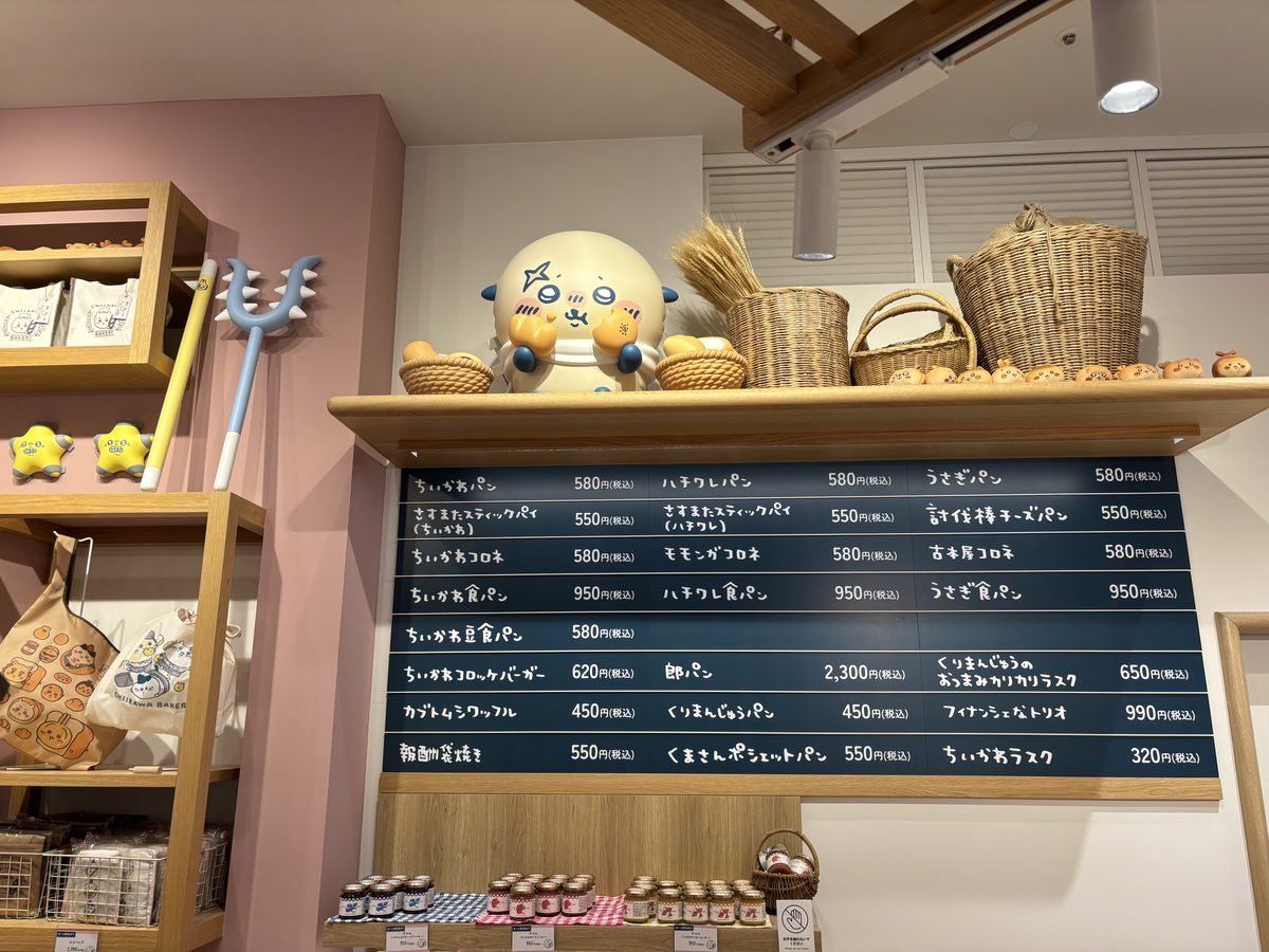 Chiikawa Bakery menu board showing character breads, drinks, and prices with a Chiikawa plush figure on top