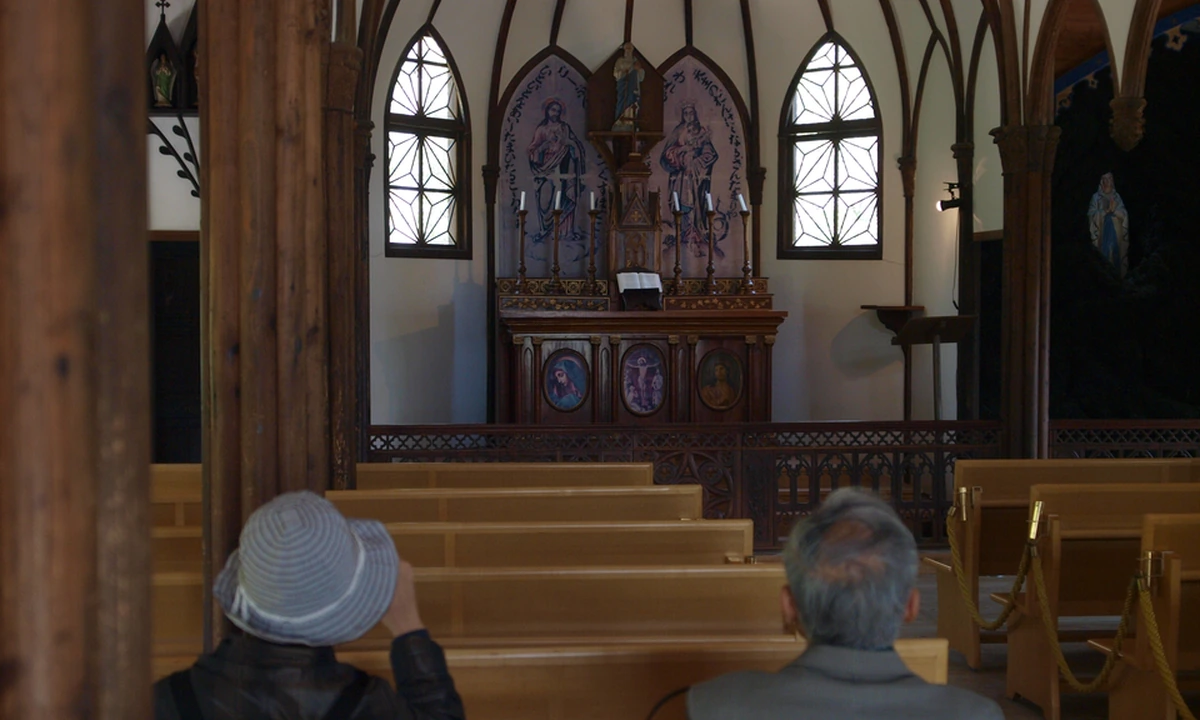 Interior of St. Paul's Church (Saint Francis Xavier Tenshudo) relocated to Museum Meiji-mura, wooden pews, Gothic-arched stained-glass windows, and altar paintings inside one of the village's most-photographed Meiji-period Western-style buildings