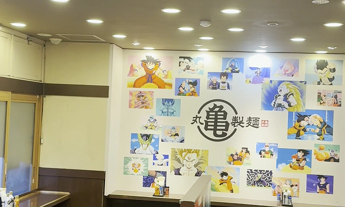 Pop-up store interior at Shinjuku-Gyoen-mae with painted Dragon Ball Z mural along the back wall, Marugame turtle logo at center, dining counters lined with stools