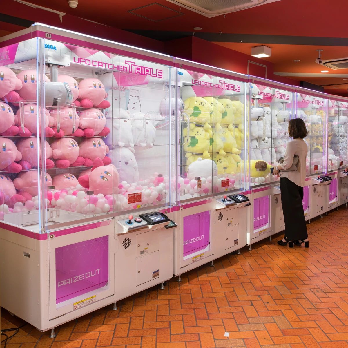 Wall of UFO catcher claw cranes packed with kawaii plush mascots inside an Akihabara game center