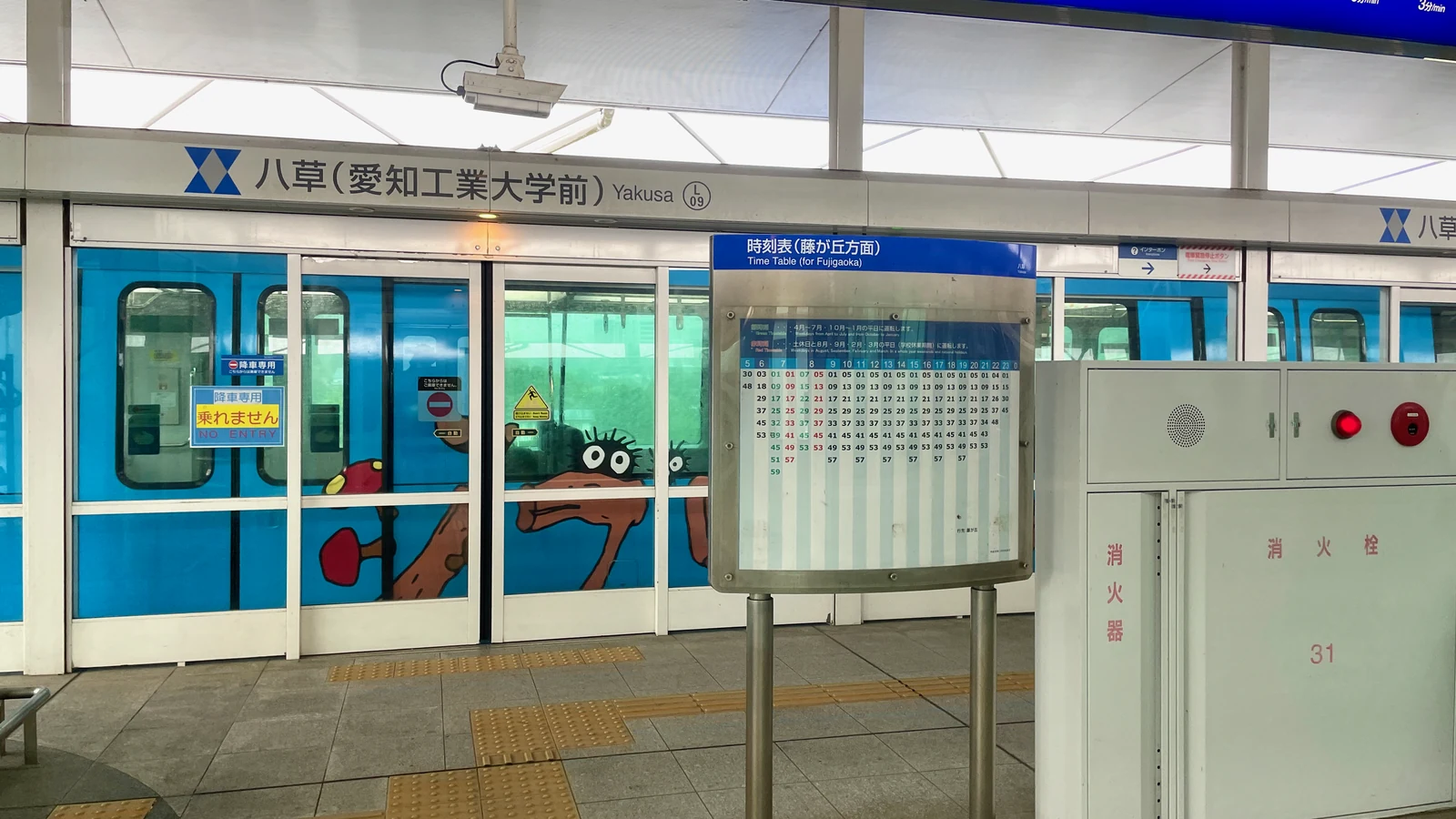 Linimo train at Yakusa Station with Ghibli Park signage on the access route to the park
