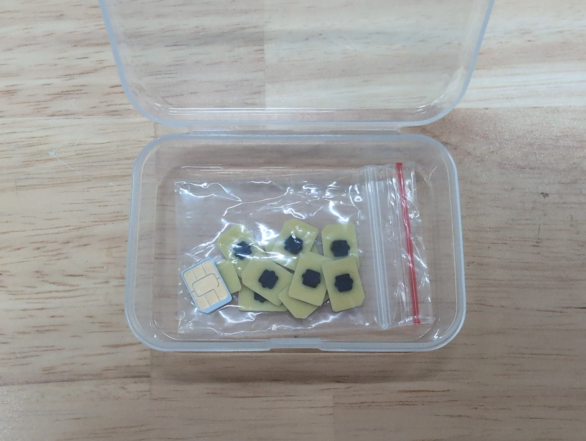 Bunch of eUICC (eSIM) chips packaged in a 4FF carrier card next to a SIM tray, illustrating how the embedded SIM technology compares to physical cards