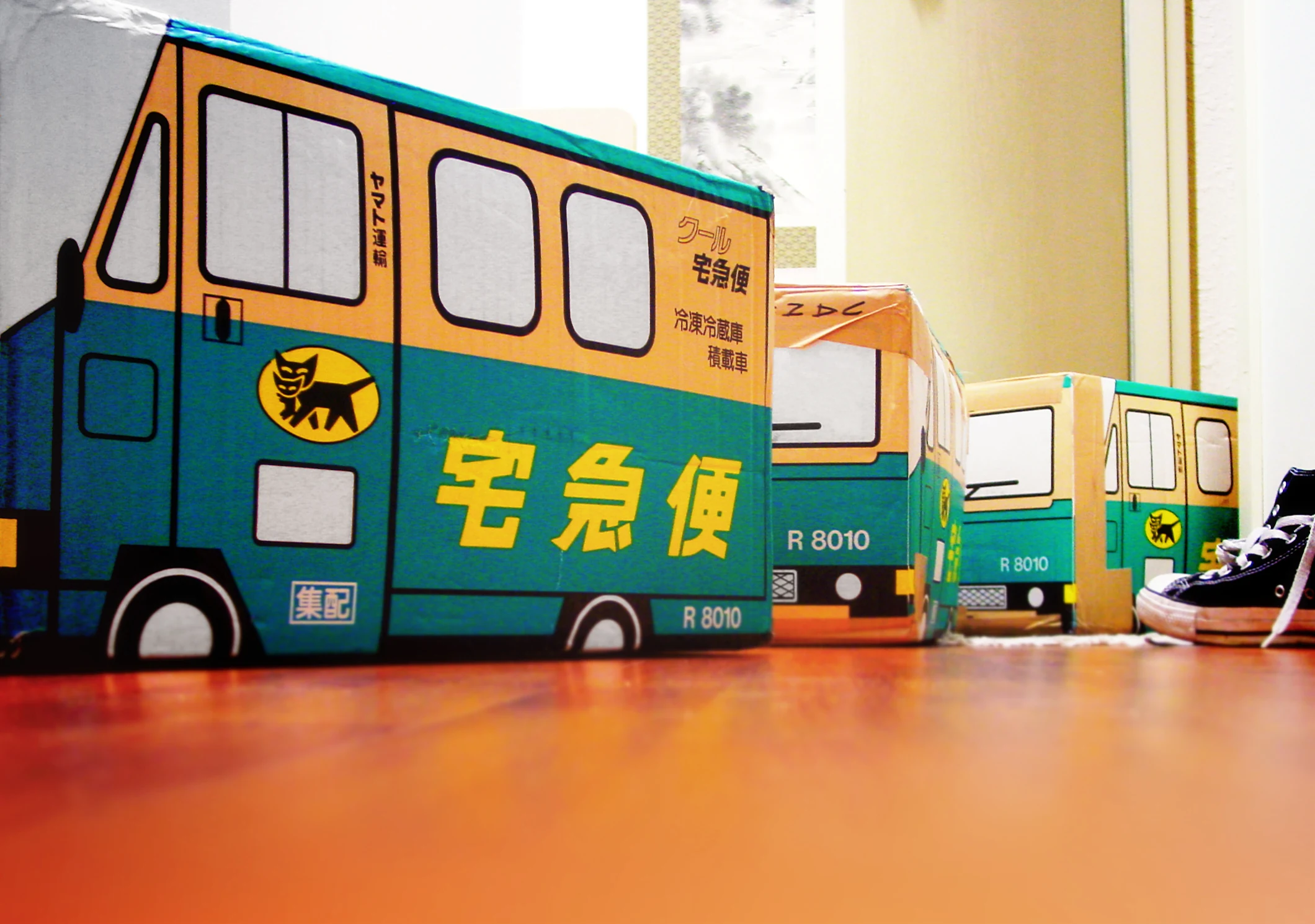 Yamato Transport Kuroneko-branded corrugated cardboard delivery boxes shaped like the company's signature green takkyubin trucks, with the kuroneko (black cat) logo stamped on each side