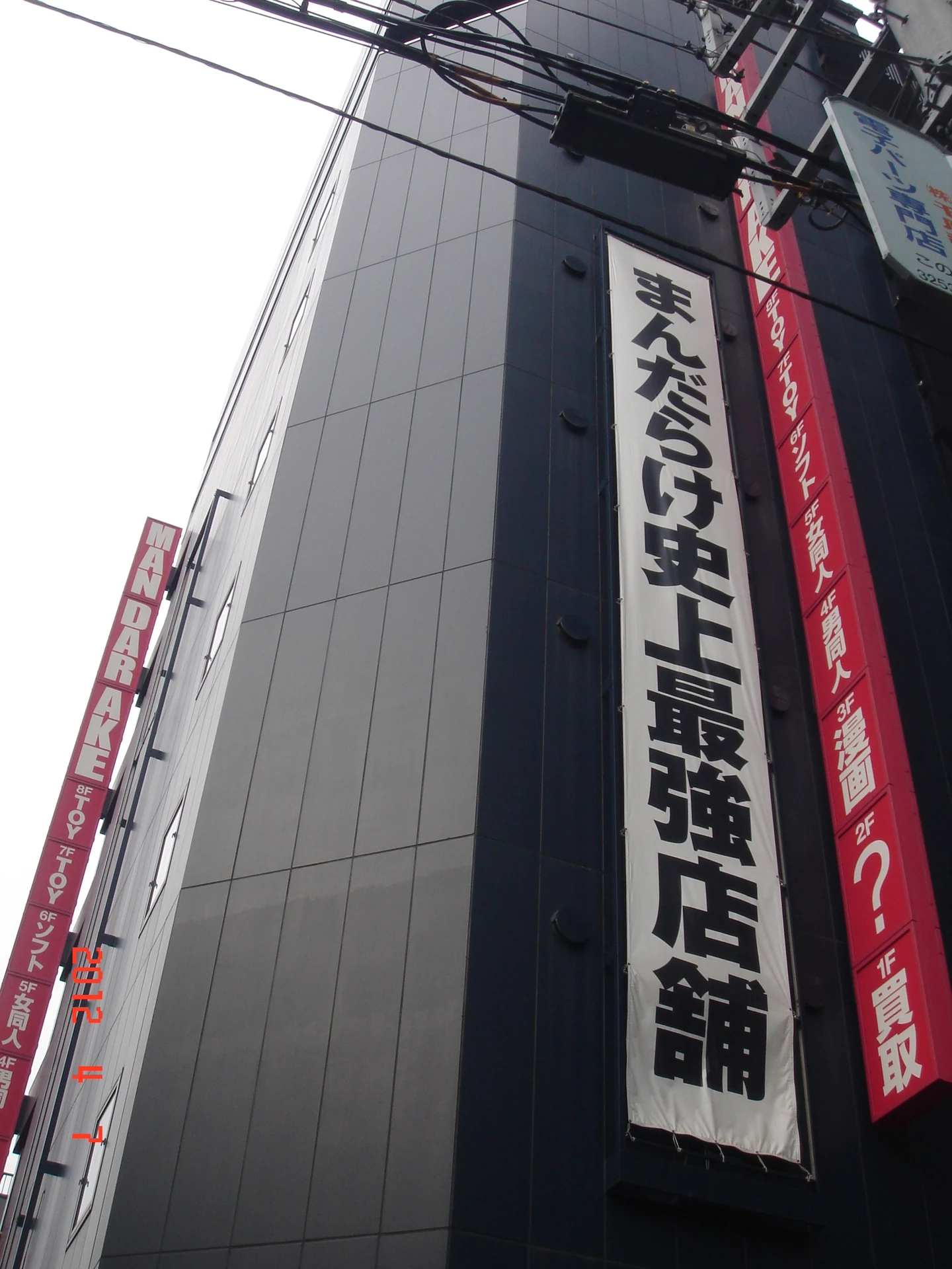 Mandarake Akihabara complex storefront with the company's red and black banners, a key source of vintage anime collectibles bought through proxy services