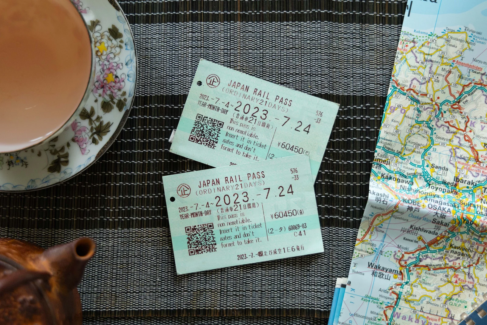 Japan Rail Pass paper tickets on a table next to a Japan rail map — used to illustrate the physical pass exchanged at JR offices