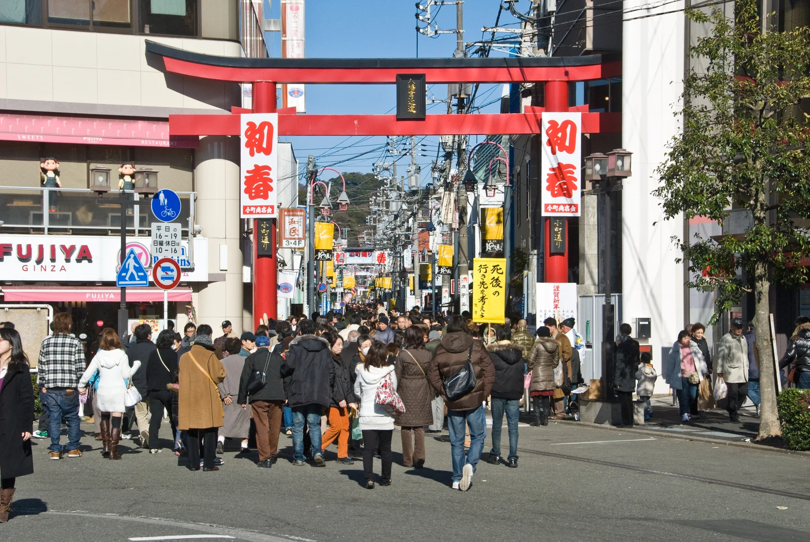 Komachi-dori shopping street entrance with the red torii gate and crowds walking under the lanterns, just east of Kamakura Station