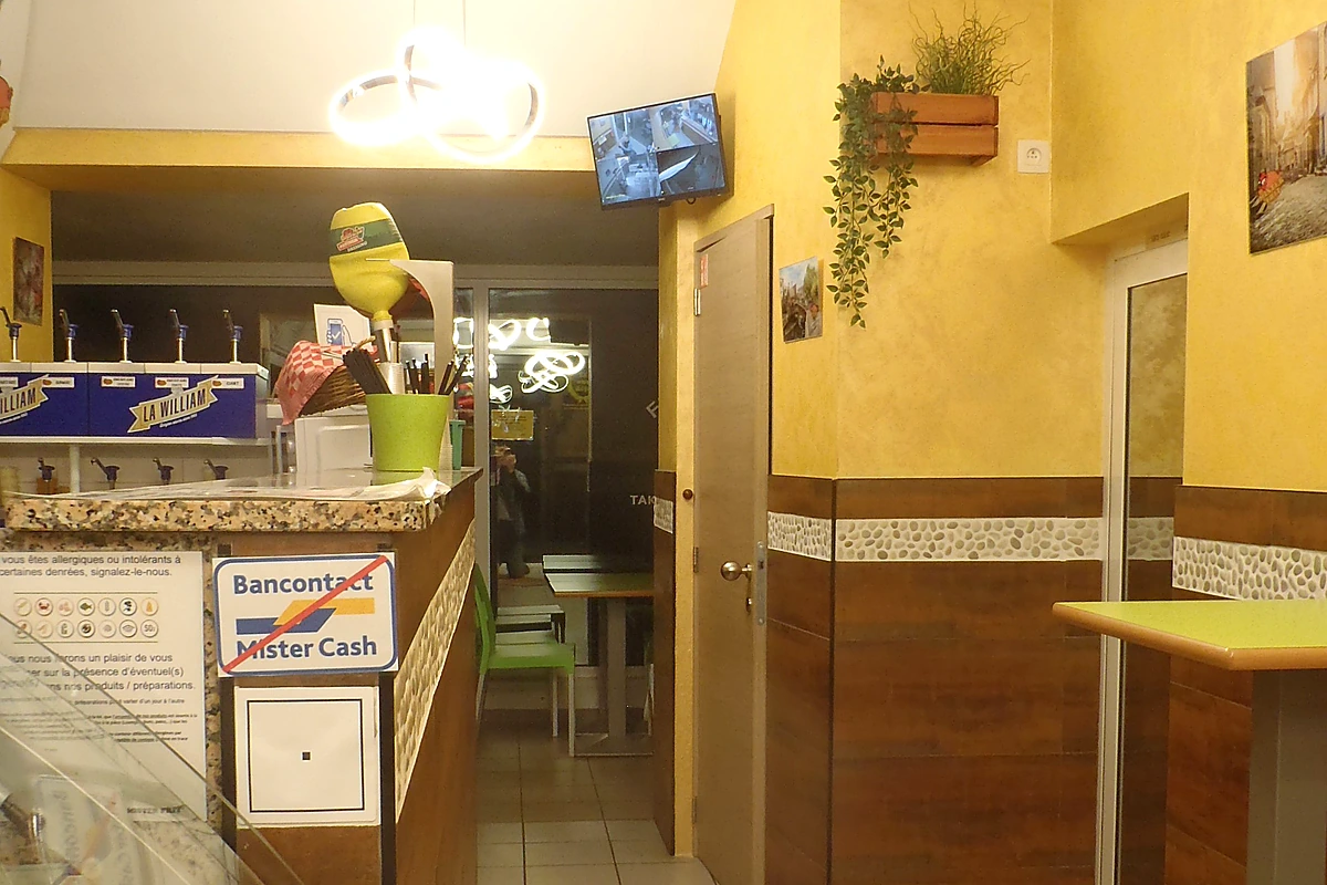 Person scanning a QR code (二次元バーコード) with a smartphone at a shop counter, demonstrating the Lawson Loppi pickup flow