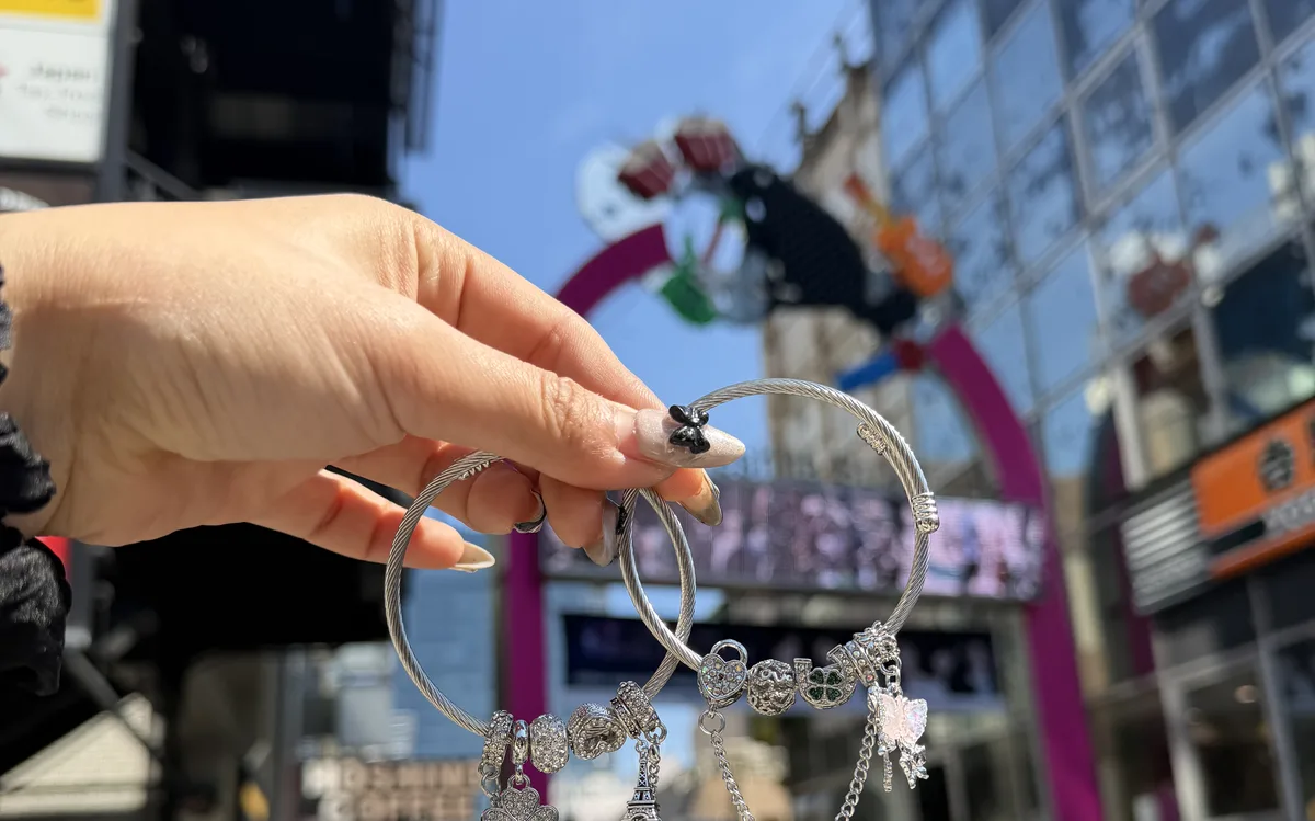 Snake bracelets held up with Harajuku Takeshita Street in the background