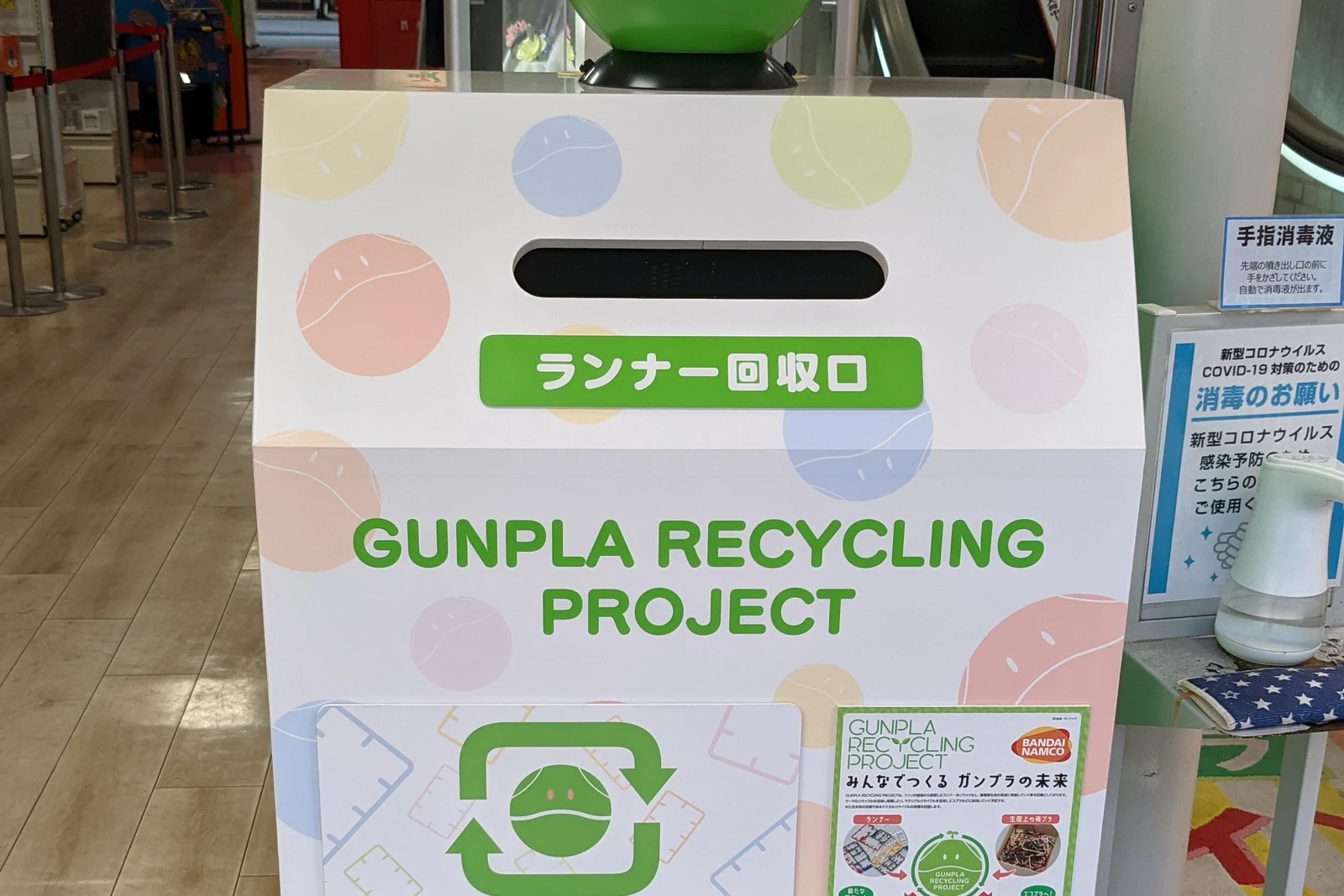 Gundam plastic-model recycling box outside Namco Nipponbashi, a signature Den Den Town street detail for Gunpla collectors