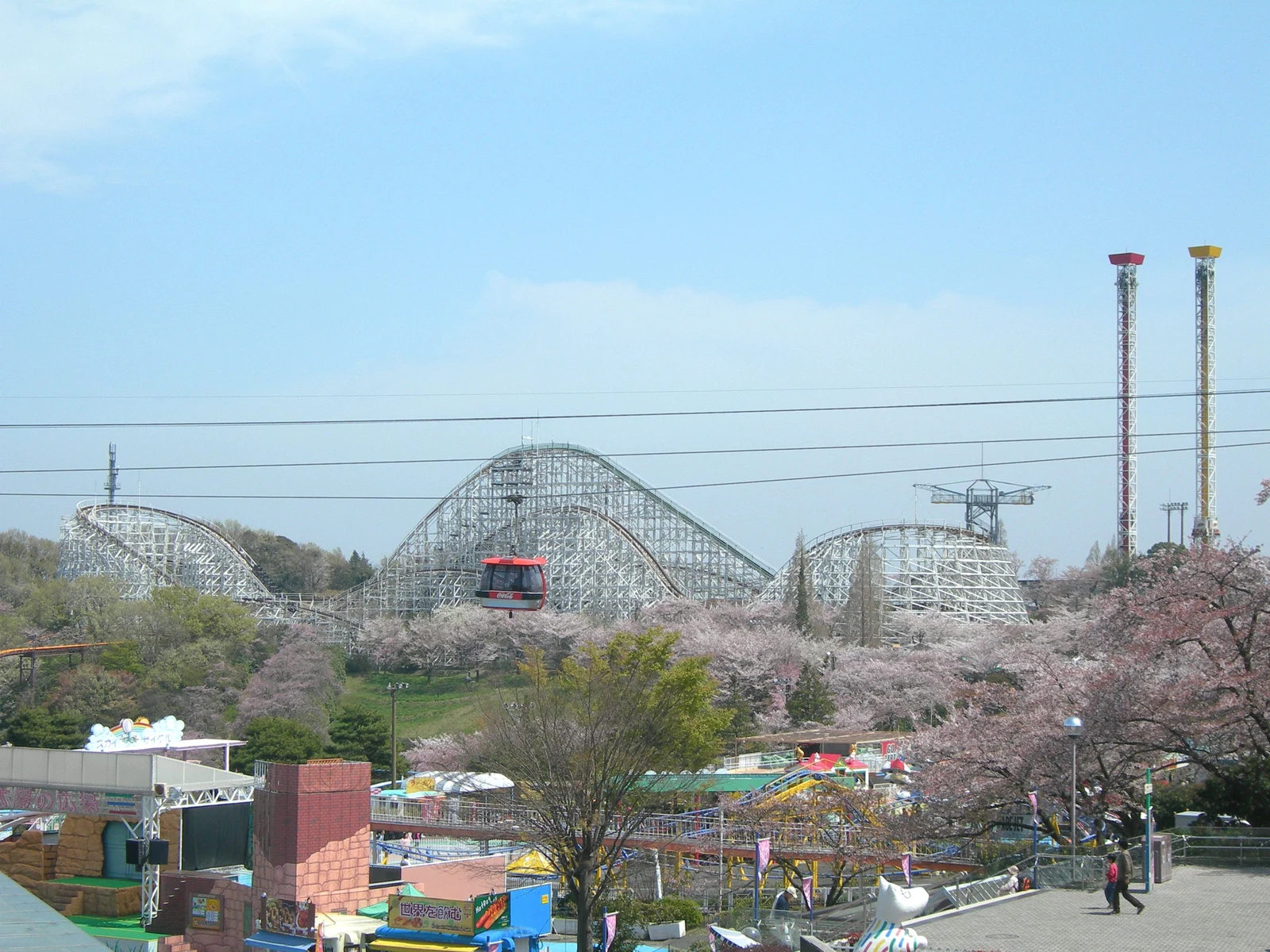 Yomiuriland park grounds with the wooden coaster and cherry blossoms, the broader Yomiuriland complex surrounding PokéPark Kanto